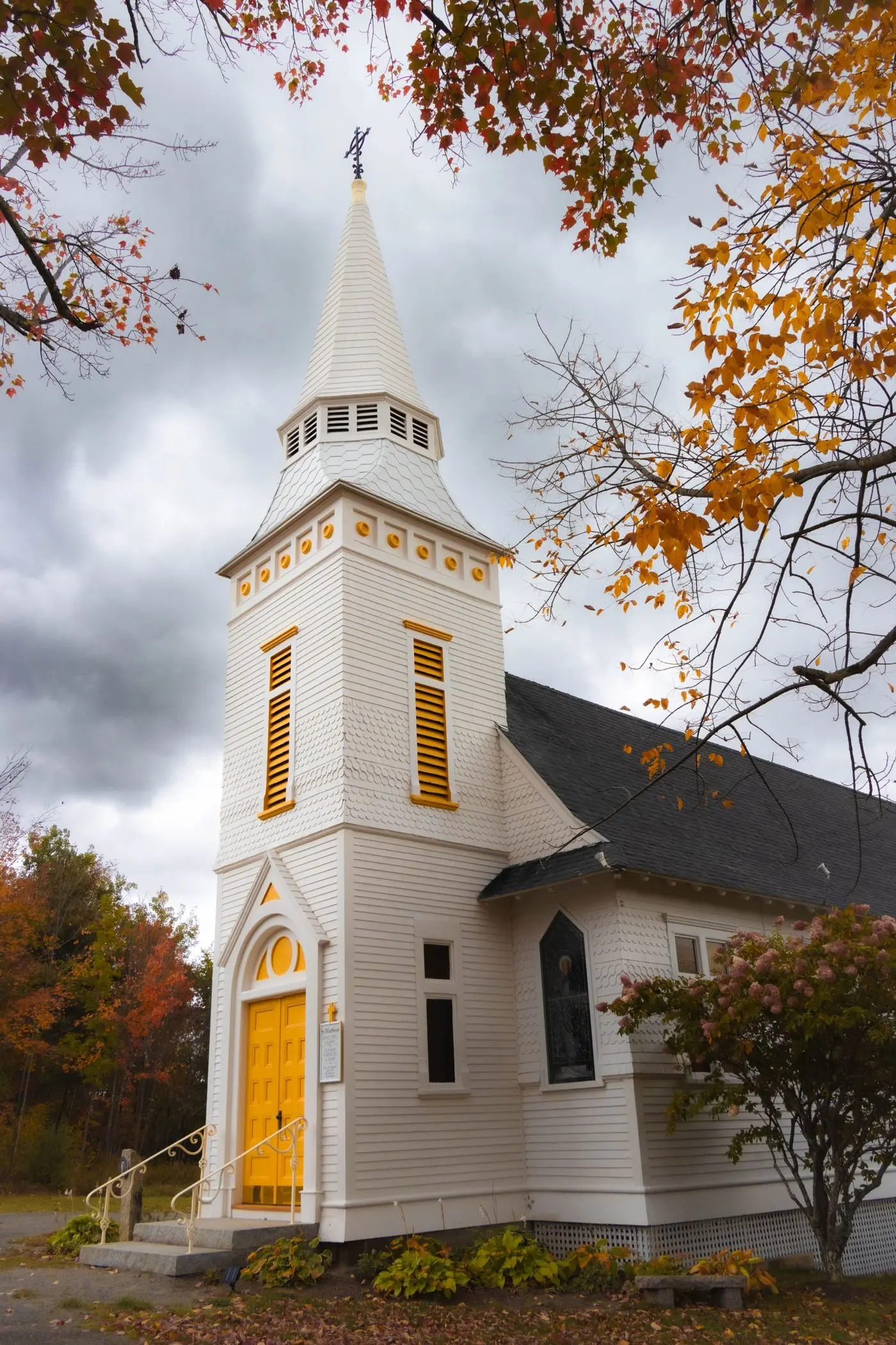 White clapboard church with a steeple among autumn trees