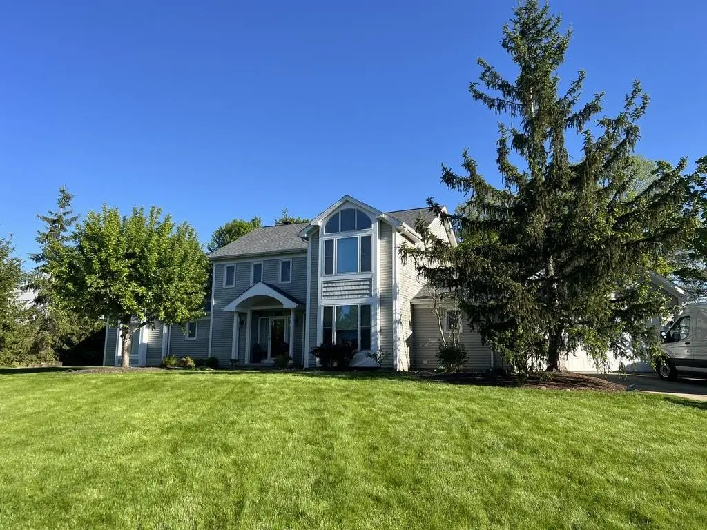 New gray shingle roof on a two-story house, seen from the lawn on a sunny day