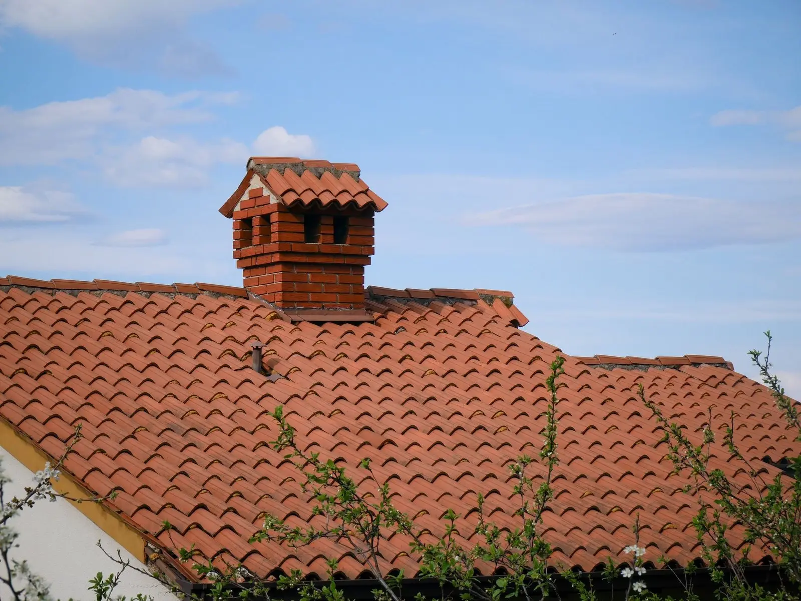 Clay tile roof with a red brick chimney